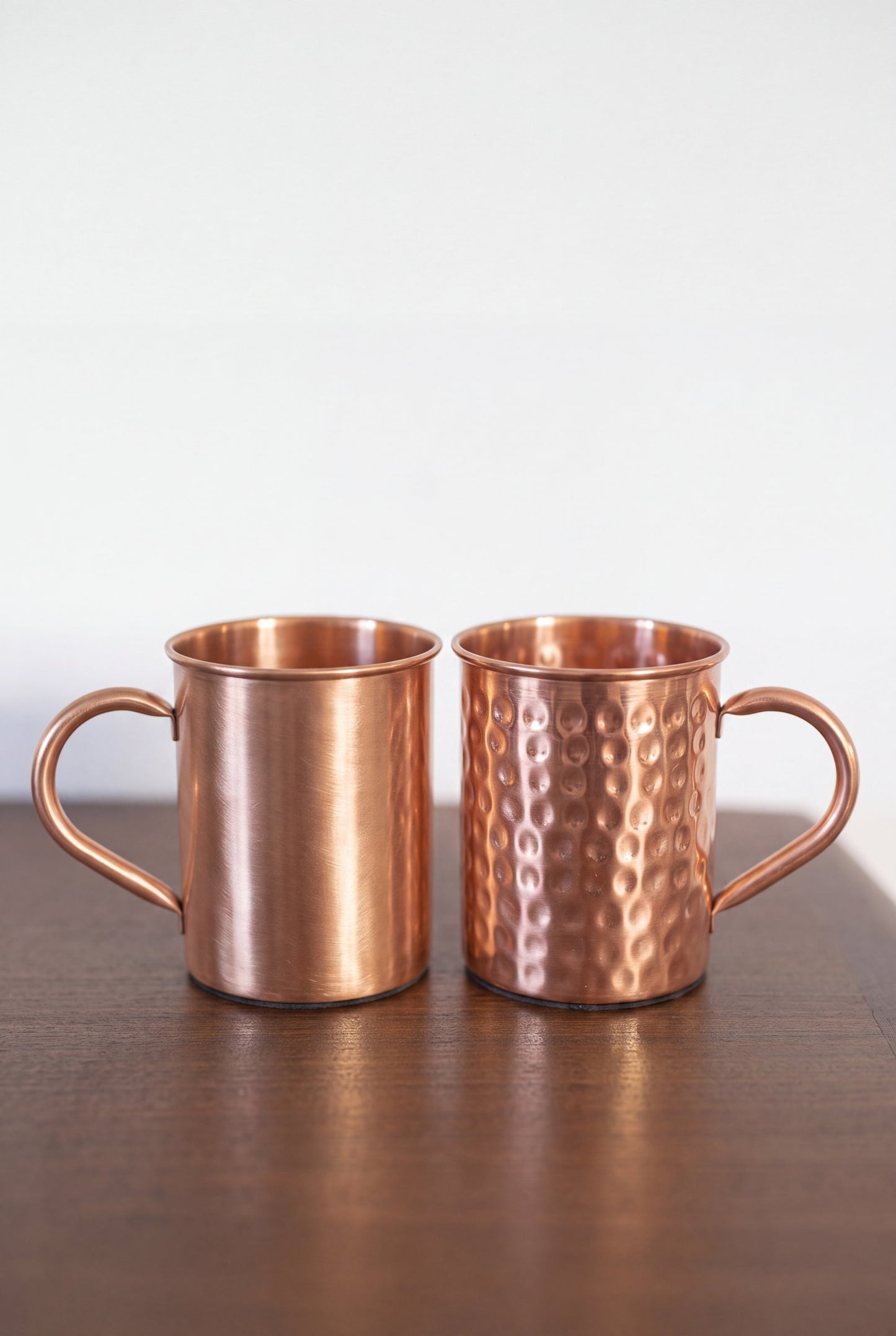 Mug en cuivre Kopero, les deux finitions côte à côte sur une table en bois