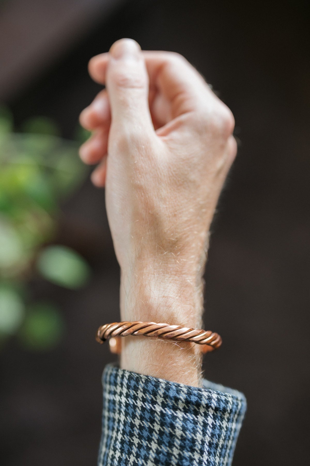 Kopero Koperen Armband Gedraaid, om de pols, met de hand omhoog tegen een donkere achtergrond