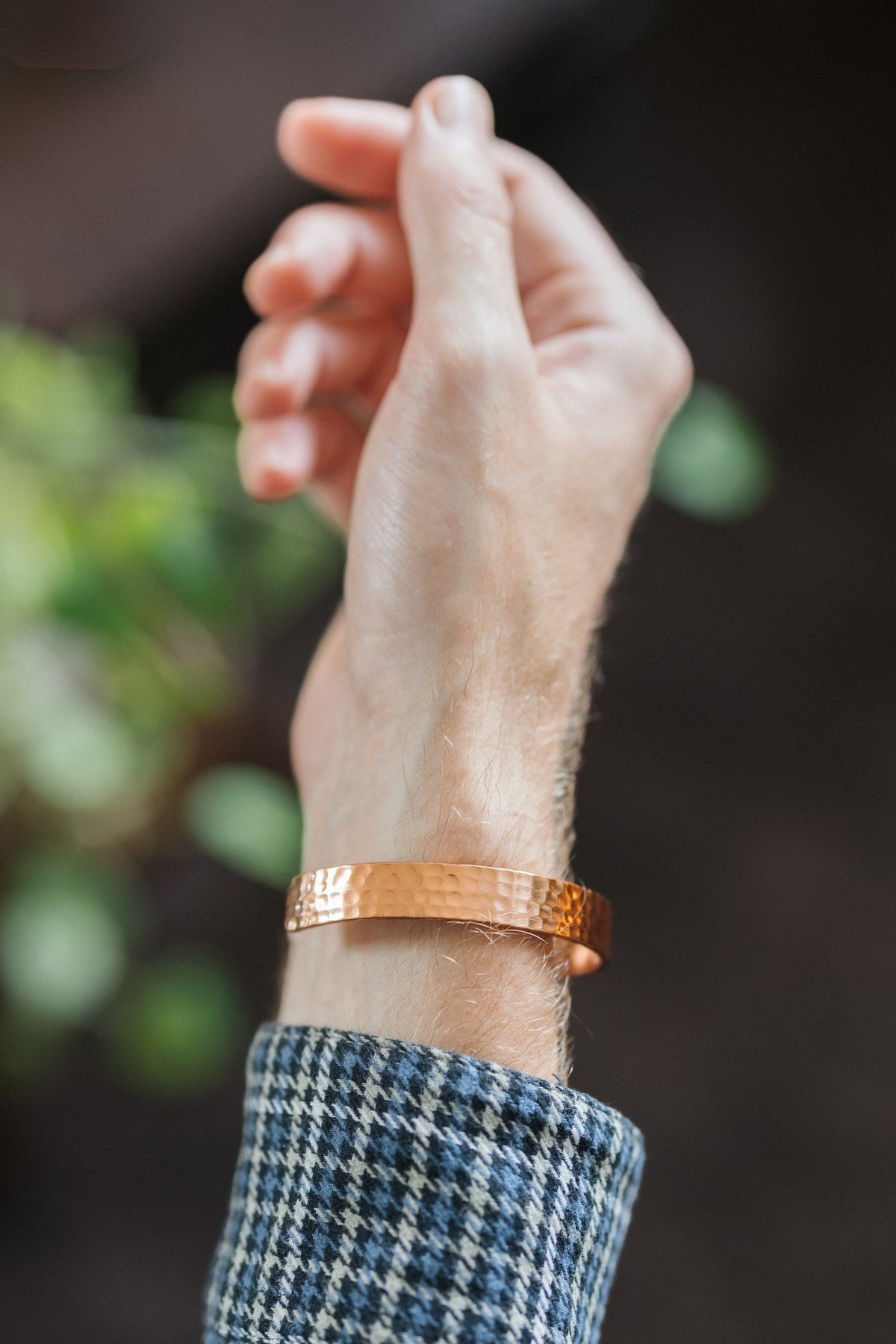Kopero Koperen Armband Gehamerd, om de pols, met de hand omhoog tegen een donkere achtergrond