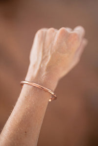 Bracelet en cuivre rond Kopero au poignet, gros plan sur le fil de cuivre