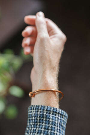Kopero Koperen Armband Rond, om de pols, met de hand omhoog tegen een donkere achtergrond
