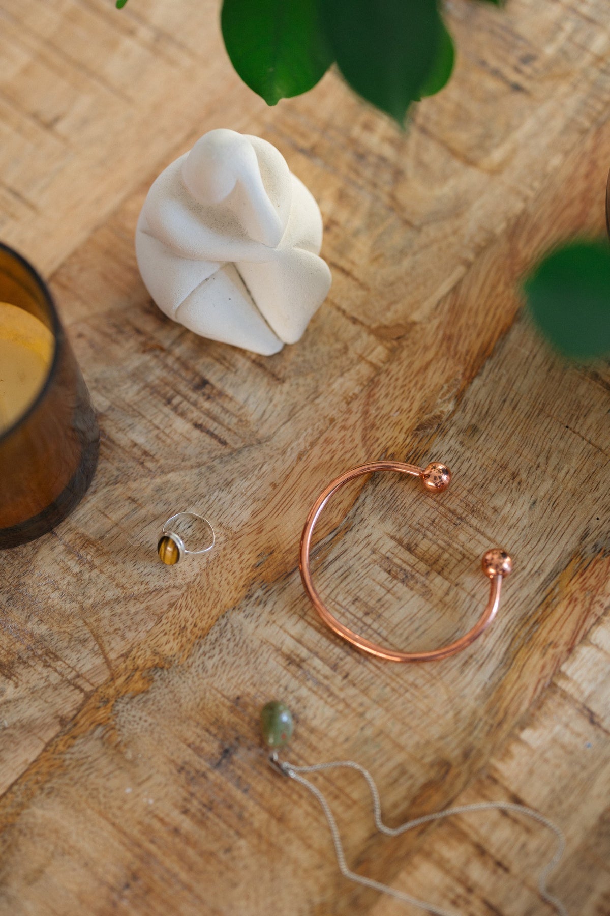 Kopero Koperen Armband Rond, op een houten tafel naast een beeldje en een ring