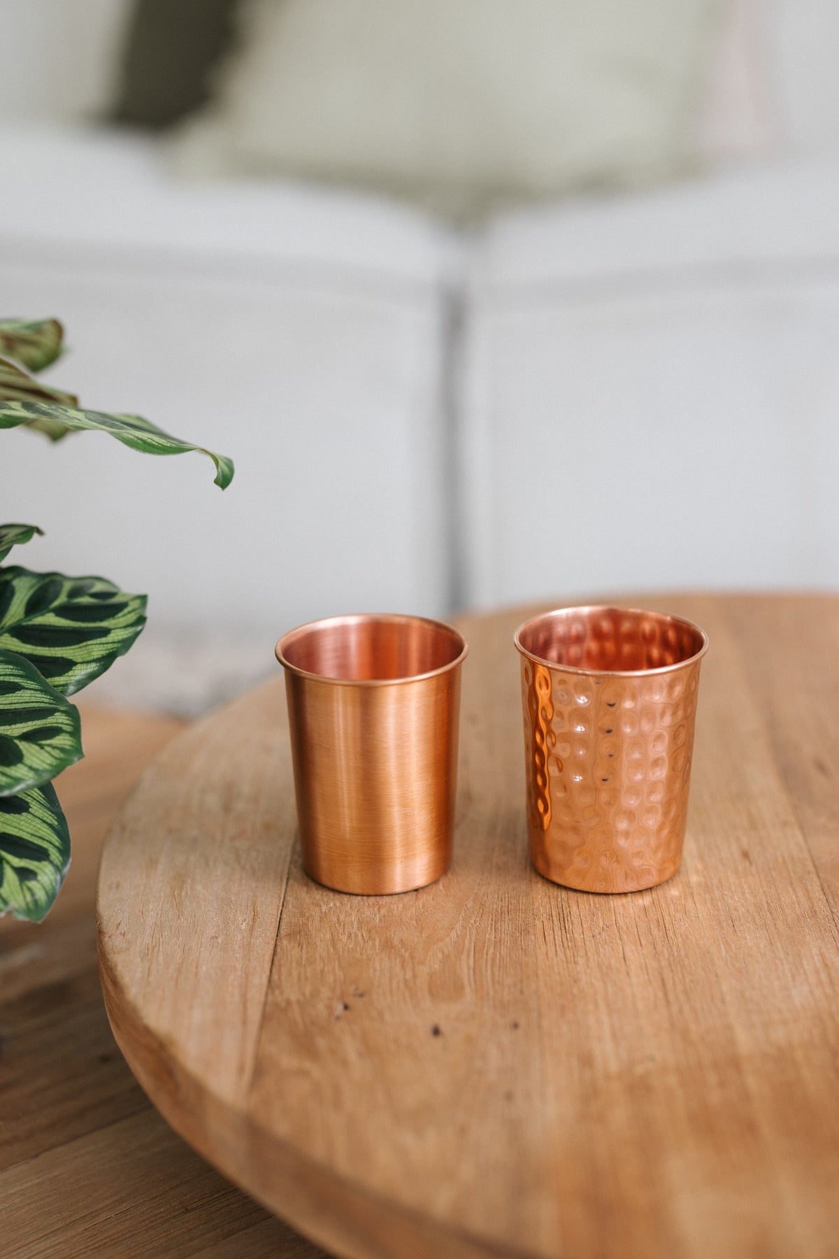 Kopero Koperen Beker, een gladde en een gehamerde beker naast elkaar op een ronde houten tafel