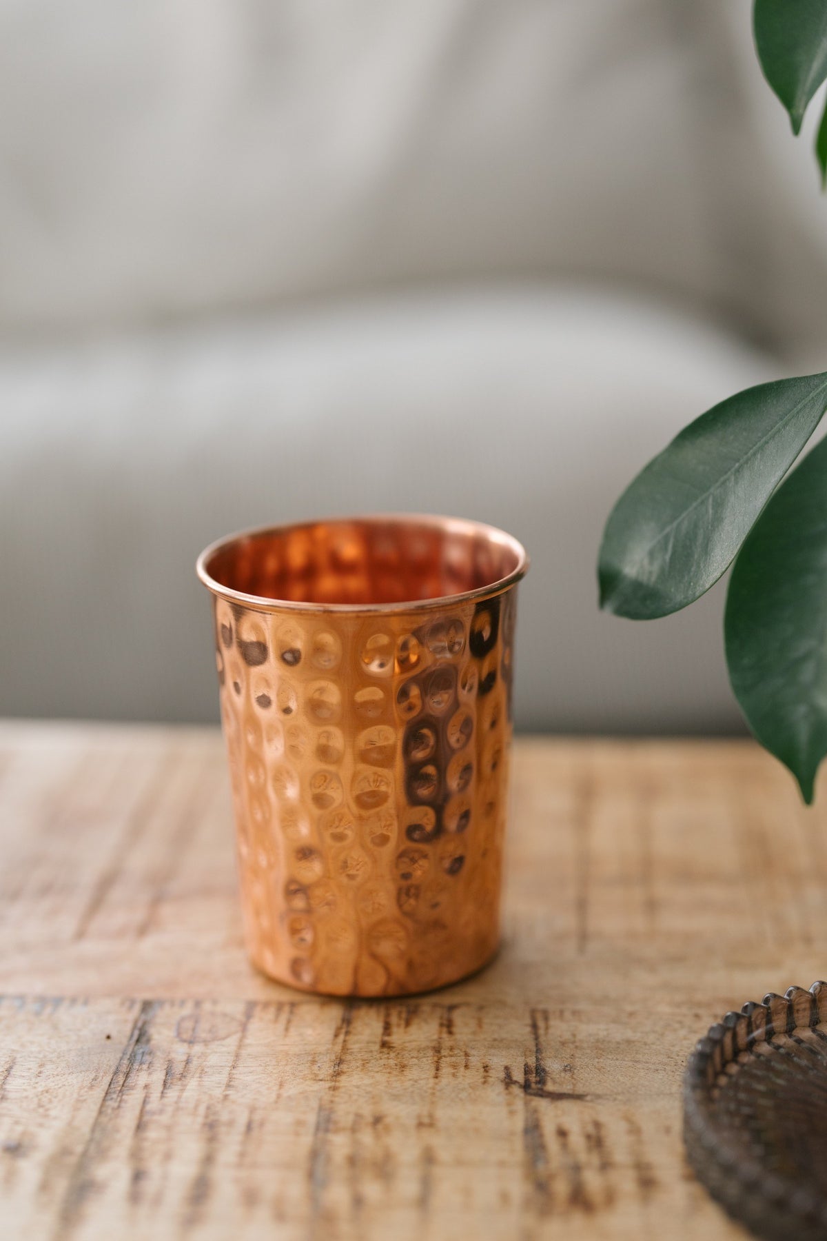 Kopero Koperen Beker Gehamerd, op een houten tafel voor een bank
