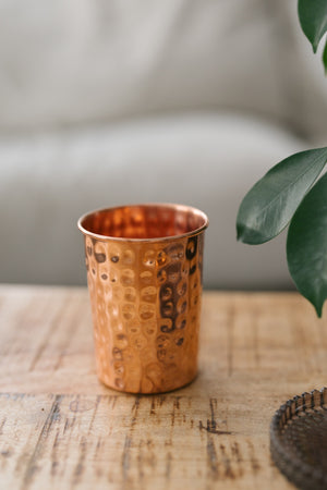 Kopero Koperen Beker Gehamerd, op een houten tafel voor een bank