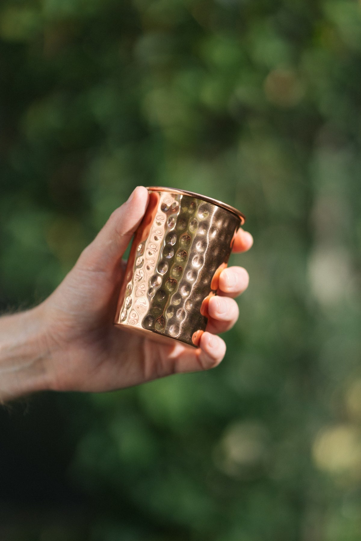 Kopero Koperen Beker Gehamerd, in een hand tegen een groene achtergrond