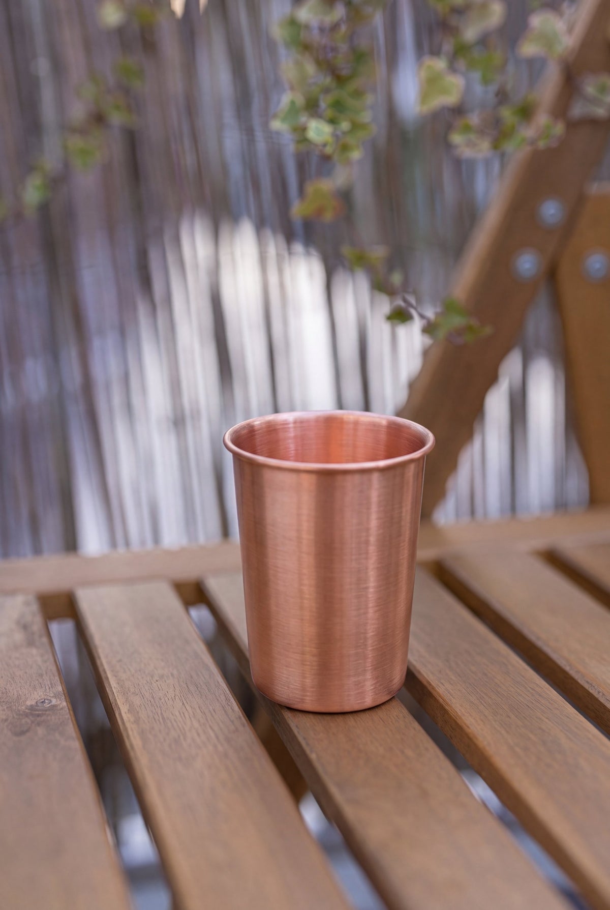 Gobelet en cuivre Kopero Lisse de 300 ml sur un banc de jardin en bois