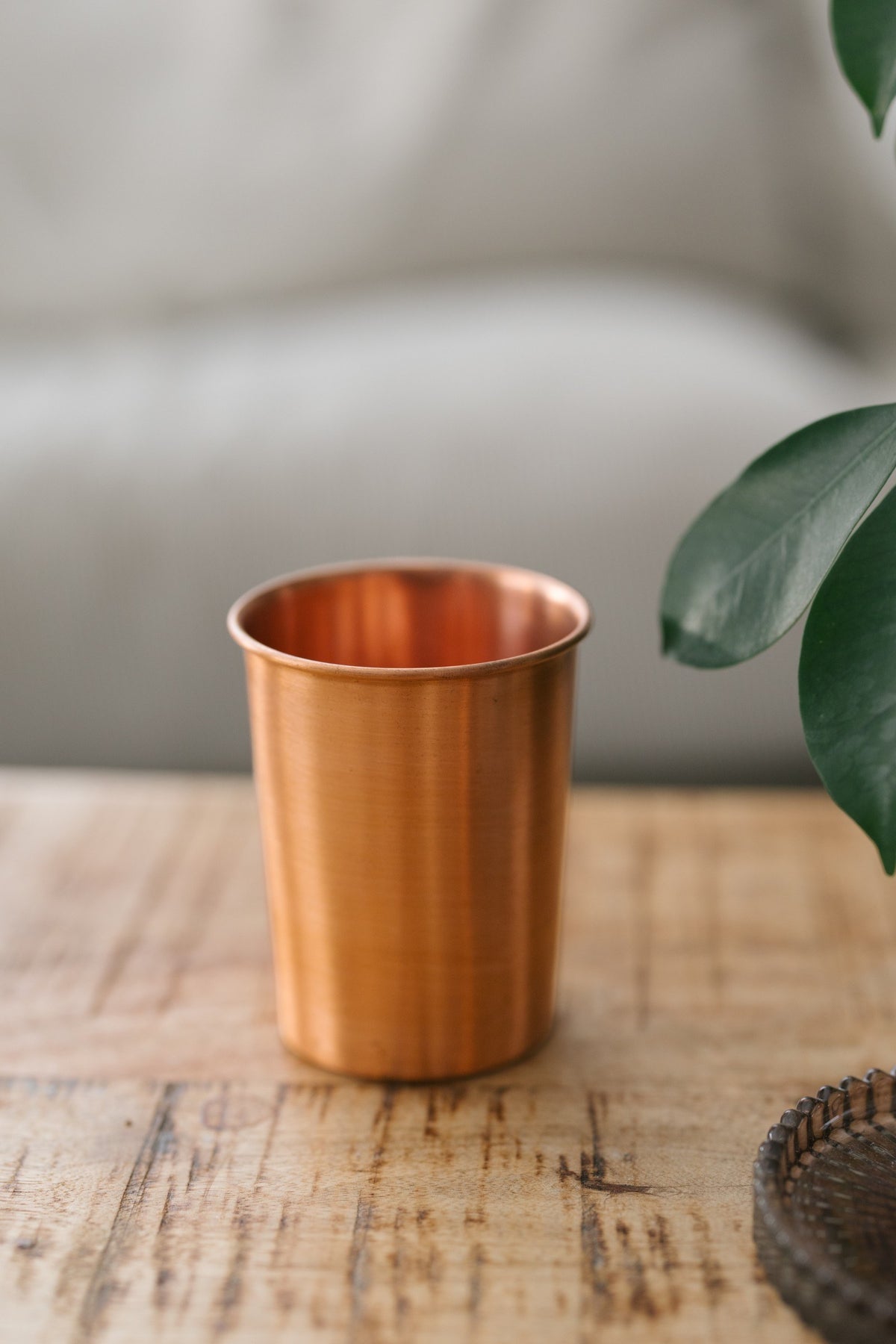 Kopero Koperen Beker Glad, op een houten tafel voor een bank