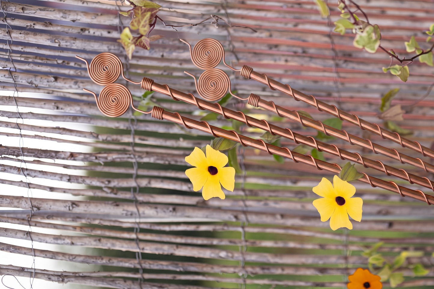 Antennes d'électroculture en cuivre Kopero de 60 cm le long d'une clôture en osier avec une plante grimpante en fleurs