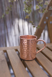 Mug en cuivre Kopero Martelé de 400 ml sur un banc de jardin en bois