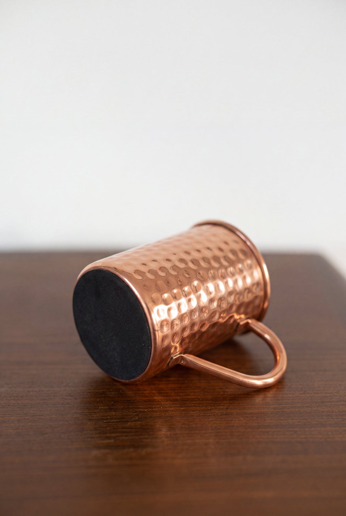Mug en cuivre Kopero Martelé posé sur le côté, avec la base en feutre visible