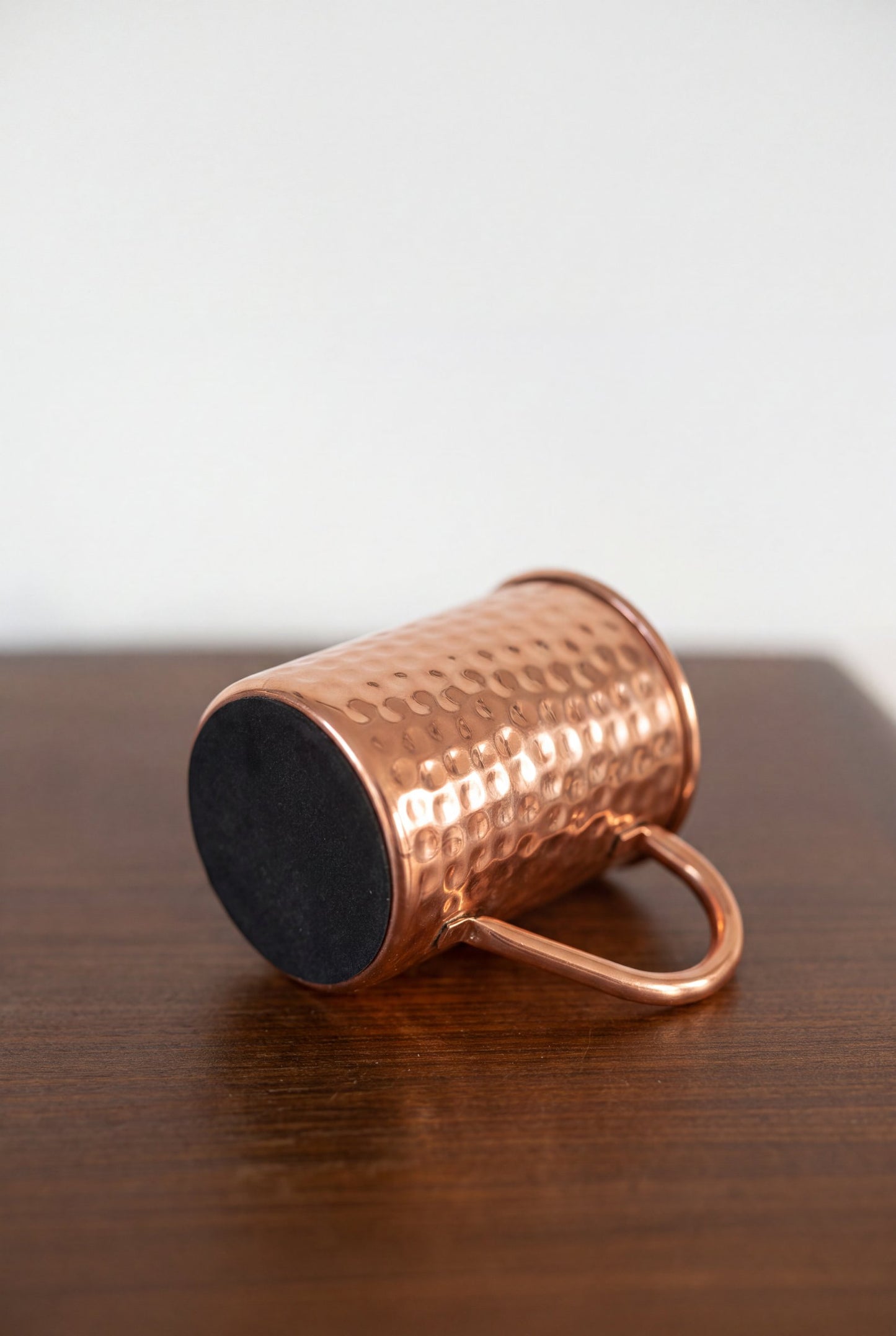 Mug en cuivre Kopero Martelé posé sur le côté, avec la base en feutre visible