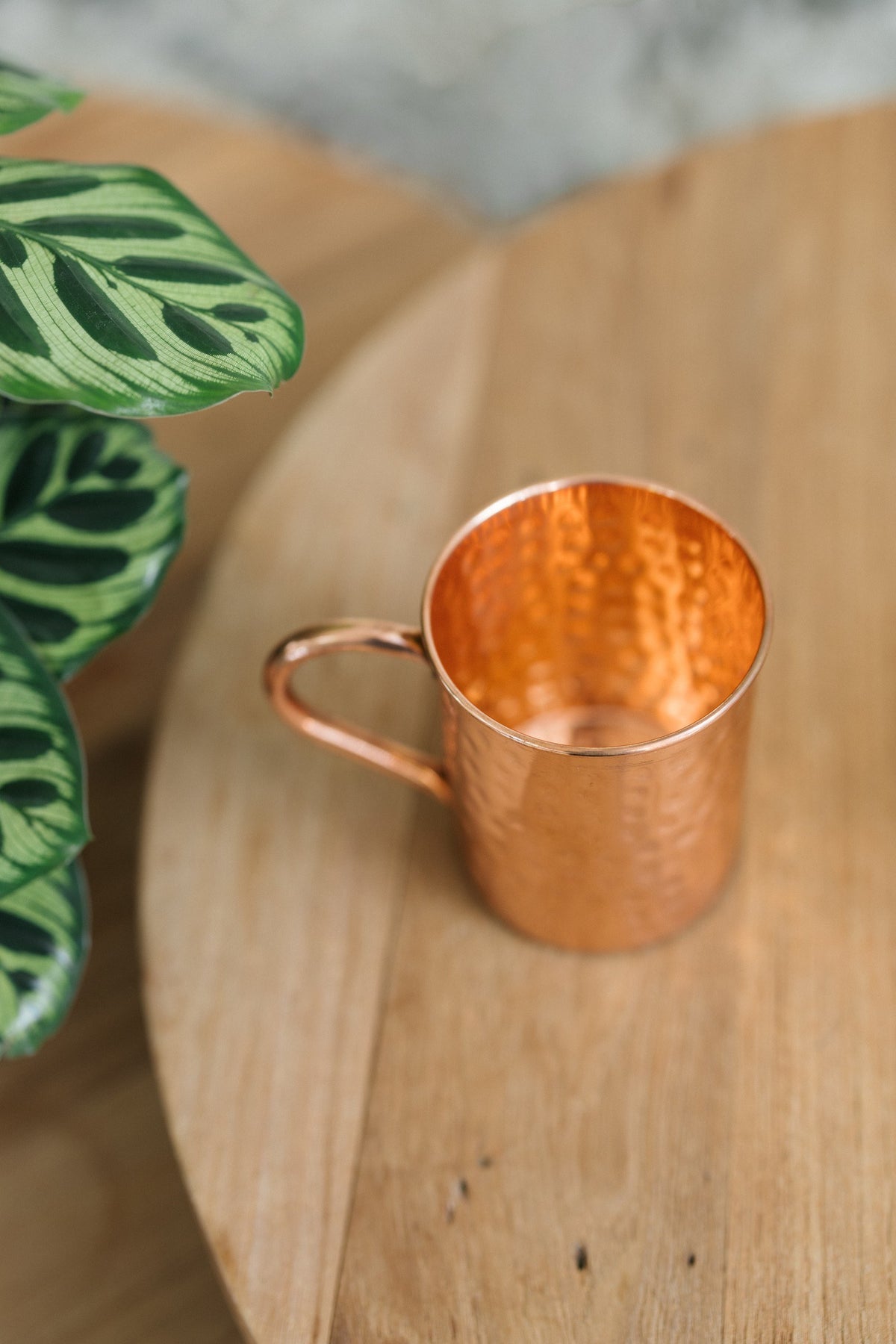 Kopero Koperen Mok Gehamerd, op zijn zij op een ronde houten tafel