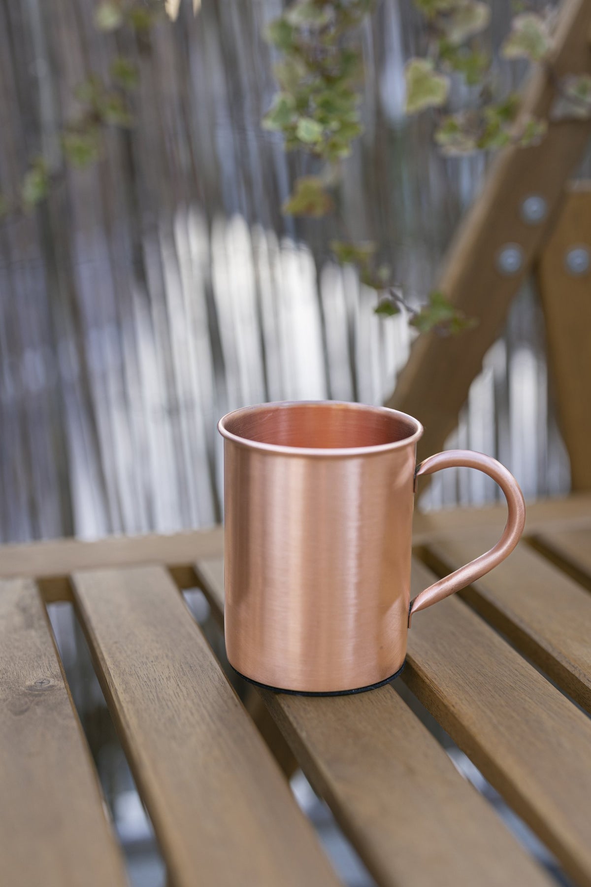 Mug en cuivre Kopero Lisse de 400 ml sur un banc de jardin en bois