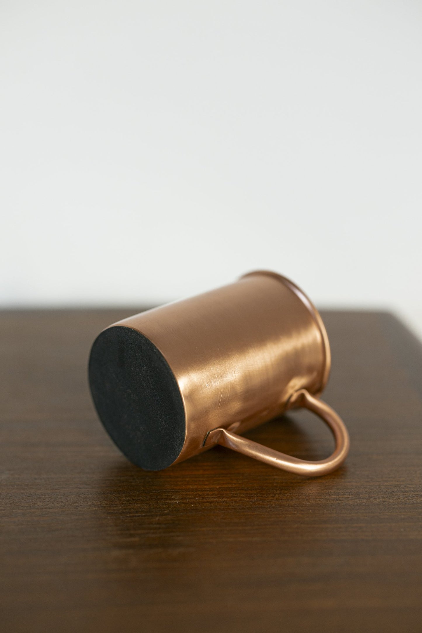 Mug en cuivre Kopero Lisse posé sur le côté, avec la base en feutre visible