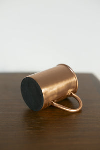 Mug en cuivre Kopero Lisse posé sur le côté, avec la base en feutre visible