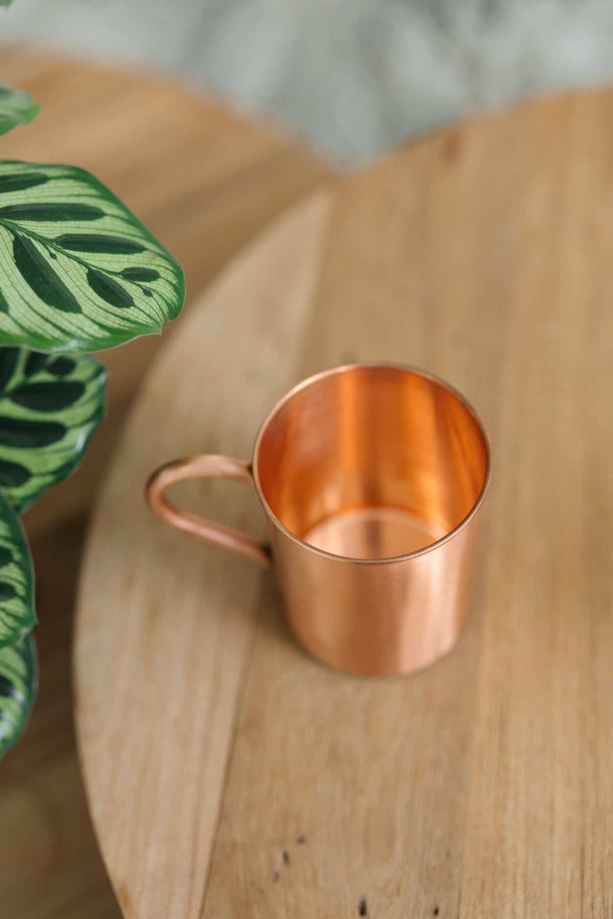 Kopero Koperen Mok Glad, op zijn zij op een ronde houten tafel