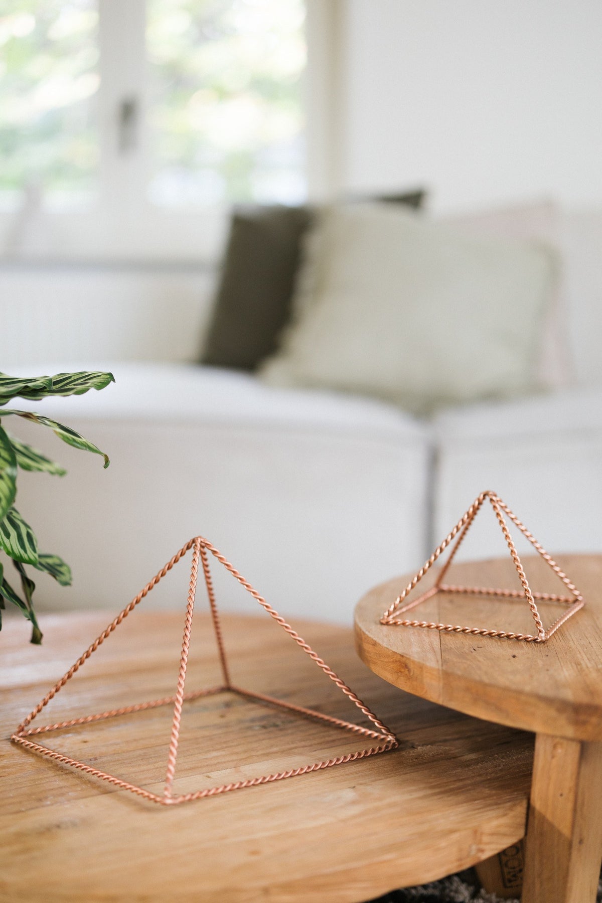 Kopero Koperen Piramide Energizer Gedraaid, de kleine en de grote piramide naast elkaar op twee houten tafels