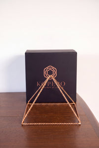Pyramide énergisante en cuivre torsadé Kopero Grande (23,56 cm) devant le coffret cadeau noir Kopero