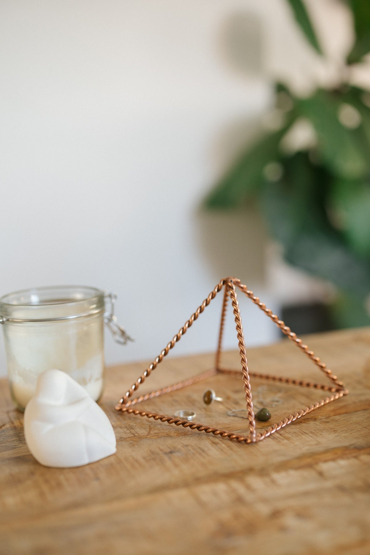 Kopero Koperen Piramide Energizer Gedraaid Klein (14,56 cm), met sieraden eronder naast een kaarsenpot en een beeldje