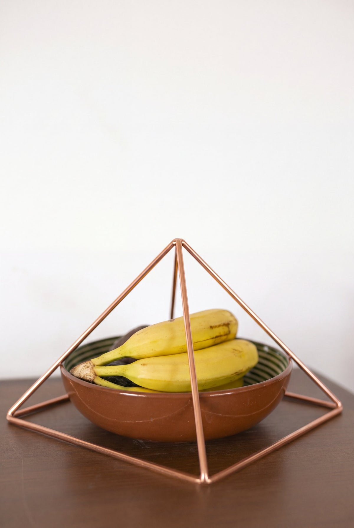 Pyramide énergisante en cuivre lisse Kopero Grande (23,56 cm) au-dessus d'une coupe de fruits
