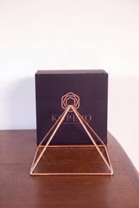 Pyramide énergisante en cuivre lisse Kopero Grande (23,56 cm) devant le coffret cadeau noir Kopero