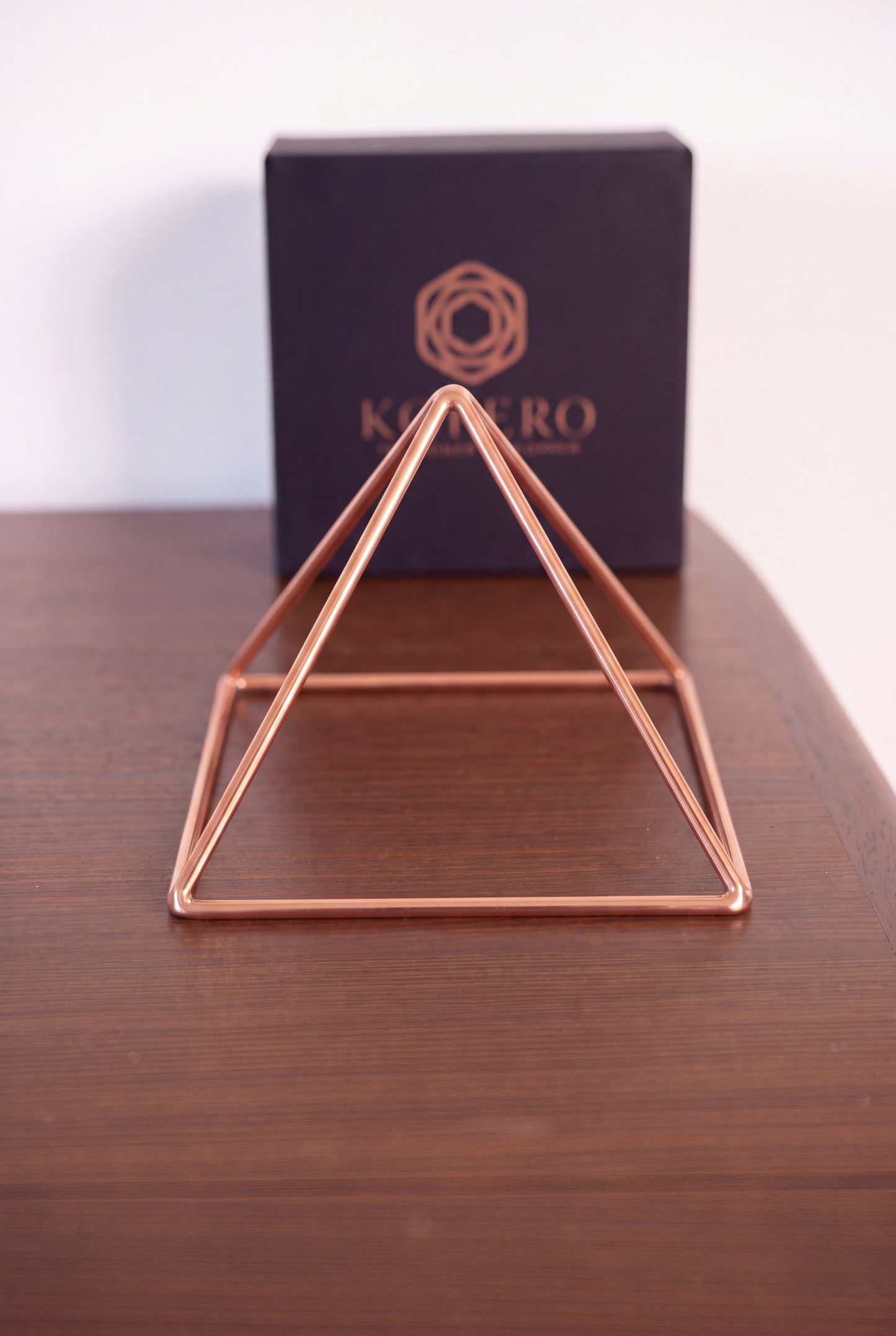 Pyramide énergisante en cuivre lisse Kopero Petite (14,56 cm) devant le coffret cadeau noir Kopero