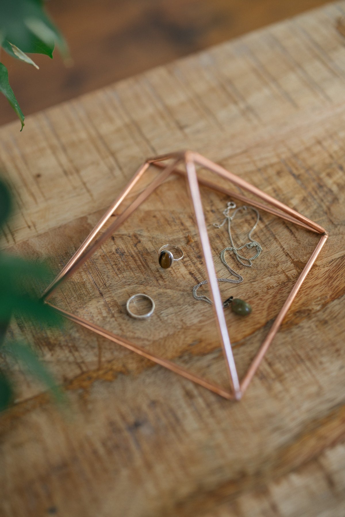 Kopero Koperen Piramide Energizer Glad Klein (14,56 cm), met sieraden eronder op een houten plank