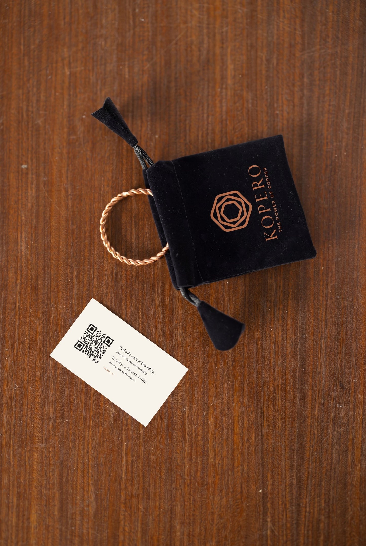 Anneau tenseur en cuivre Kopero à côté de la pochette en velours et de la carte avec code QR