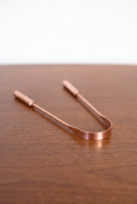 Racle-langue en cuivre Kopero en cuivre pur sur une table en bois