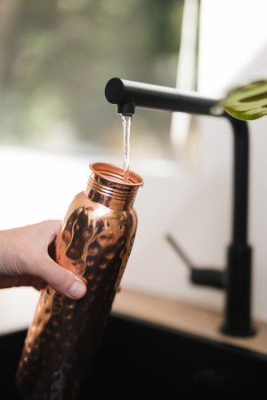Kopero Koperen Waterfles Gehamerd, onder de kraan, terwijl er water in stroomt