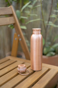 Gourde en cuivre Kopero Lisse avec le bouchon détaché sur une chaise de jardin en bois