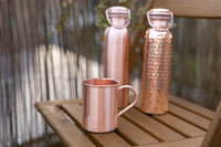 Gourdes en cuivre Kopero Lisse et Martelée avec une tasse en cuivre assortie sur une table de jardin